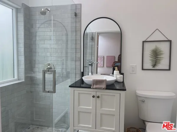 a bathroom with a granite countertop sink a toilet and shower