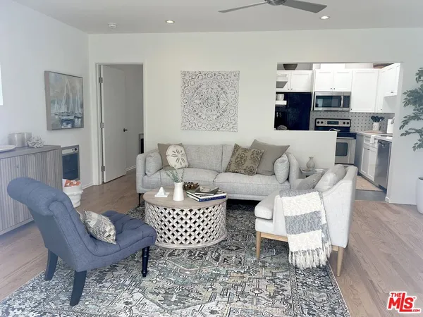 a living room with furniture a rug and kitchen view