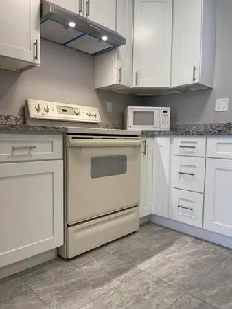 a kitchen with granite countertop white cabinets and white appliances