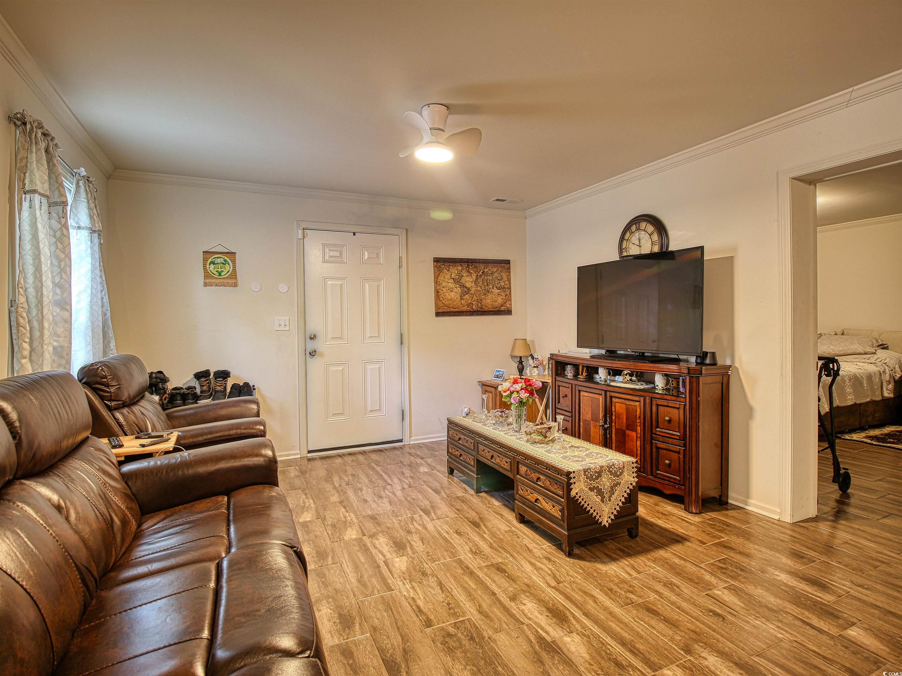 215 West James Street Mullins, SC 29574 - Photo 5 of 18 Living area with ornamental molding, light wood-style flooring, and ceiling fan