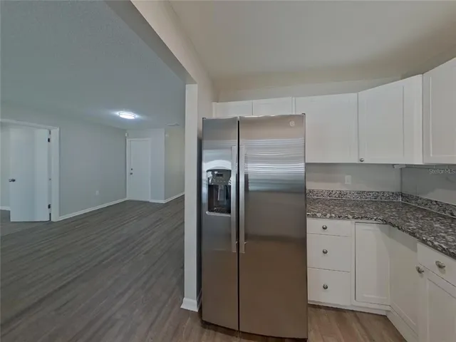 a kitchen with granite countertop stainless steel appliances a refrigerator and cabinets