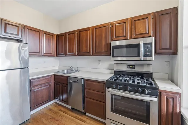 a kitchen with cabinets stainless steel appliances and wooden floor