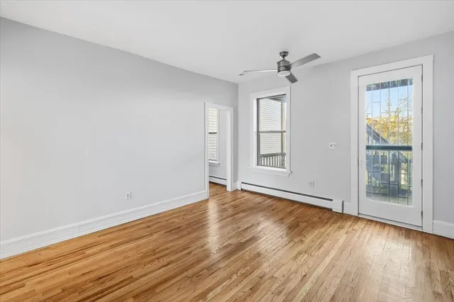 an empty room with wooden floor ceiling fan and windows