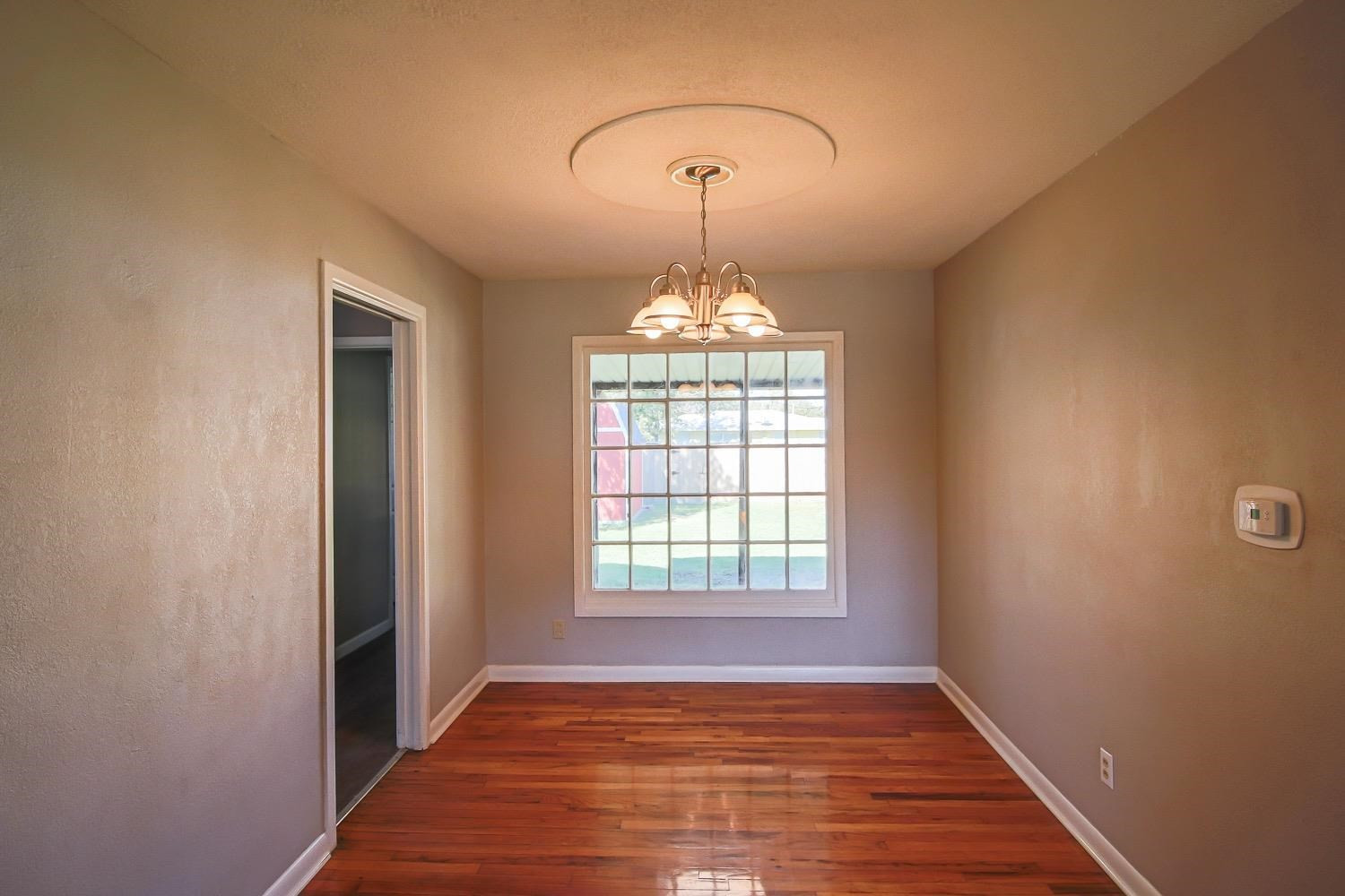 3814 32nd Street Lubbock, TX 79410 - Photo 6 of 10 an empty room with wooden floor chandelier and windows