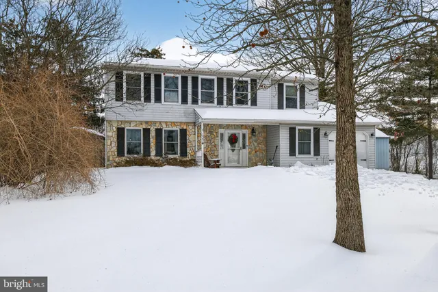 a front view of a house with a yard covered with snow