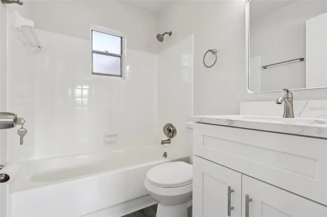 a bathroom with a granite countertop toilet a sink and a bathtub