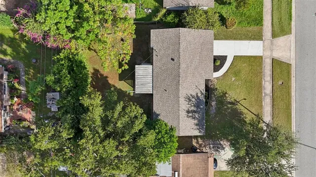 an aerial view of a house with a yard and large tree