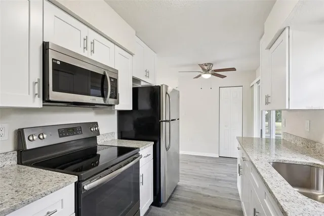 a kitchen with stainless steel appliances granite countertop a sink microwave and refrigerator