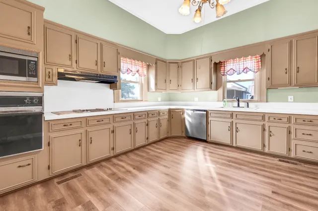 a kitchen with cabinets appliances a sink and a window