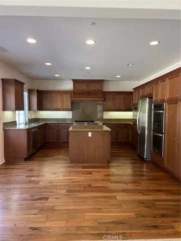 a large kitchen with stainless steel appliances a refrigerator and a stove top oven