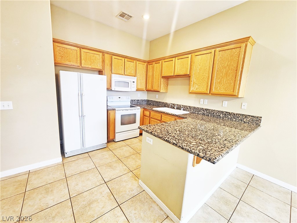 1421 Star Road, Unit 2 Pahrump, NV 89048 - Photo 7 of 33 Kitchen featuring a sink, white appliances, a peninsula, light tile patterned floors, and visible vents