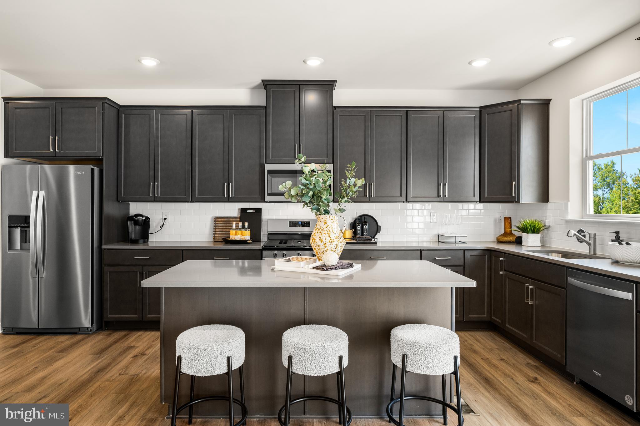a kitchen with kitchen island granite countertop a sink cabinets and stainless steel appliances