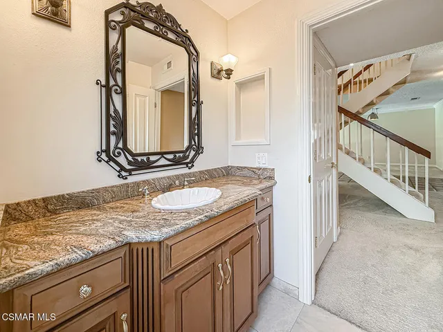 a bathroom with a granite countertop sink and a mirror