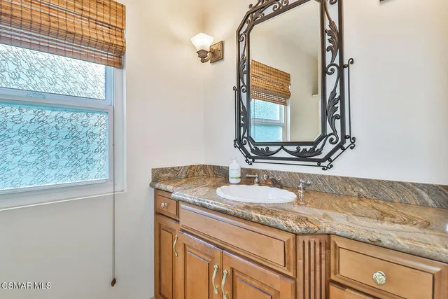 a bathroom with a granite countertop sink and a mirror