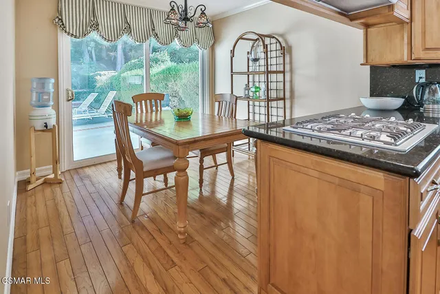 a kitchen with stainless steel appliances granite countertop a stove top oven a sink dishwasher and a dining table with wooden floor