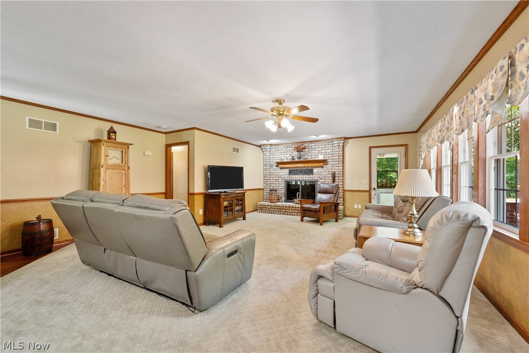 10400 Stoneacre Road Northwest Canal Fulton, OH 44614 - Photo 4 of 44 Living area featuring ceiling fan, crown molding, light colored carpet, and a fireplace