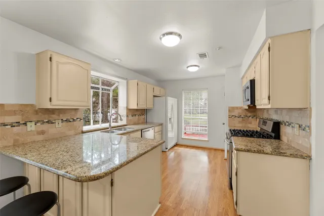 a kitchen with stainless steel appliances granite countertop a sink dishwasher stove and refrigerator with wooden floor