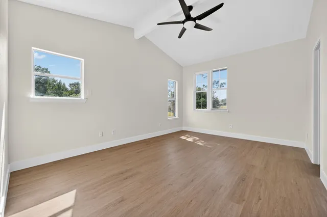 a view of empty room with wooden floor and ceiling fan