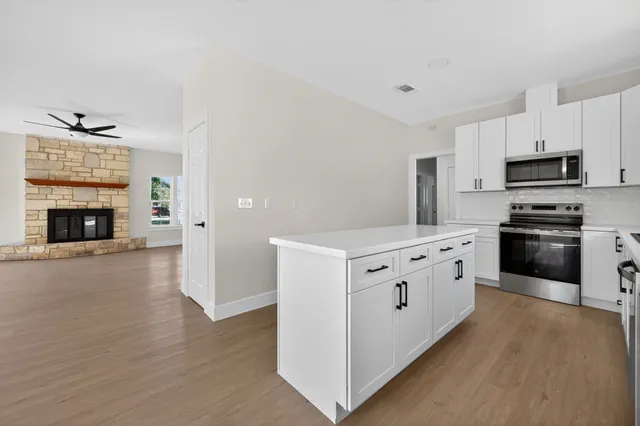 a kitchen with stainless steel appliances a stove top oven a refrigerator a sink and dishwasher with wooden floor