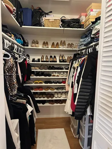 a view of walk in closet with clothes and shoes