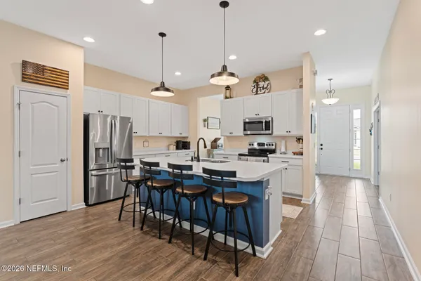 a kitchen with stainless steel appliances kitchen island granite countertop a refrigerator a stove a sink dishwasher and a dining table with wooden floor