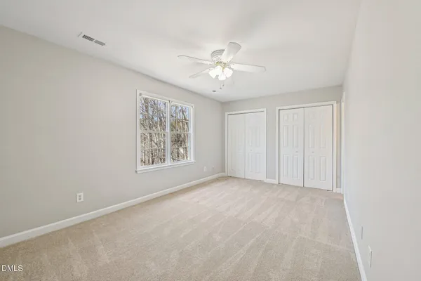 a view of an empty room and a chandelier fan