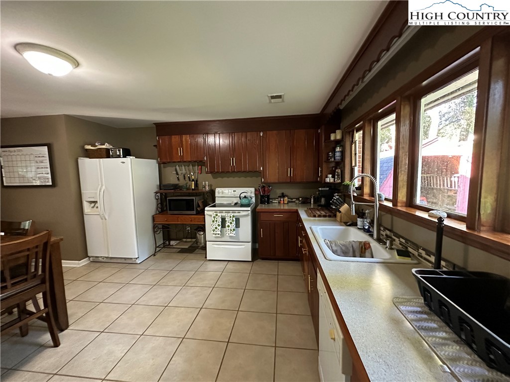 320 North Main Street Jefferson, NC 28640 - Photo 12 of 28 a kitchen with stainless steel appliances a refrigerator a sink a stove and white cabinets