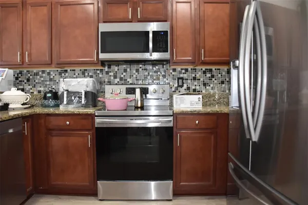 a kitchen with stainless steel appliances granite countertop a refrigerator stove and sink