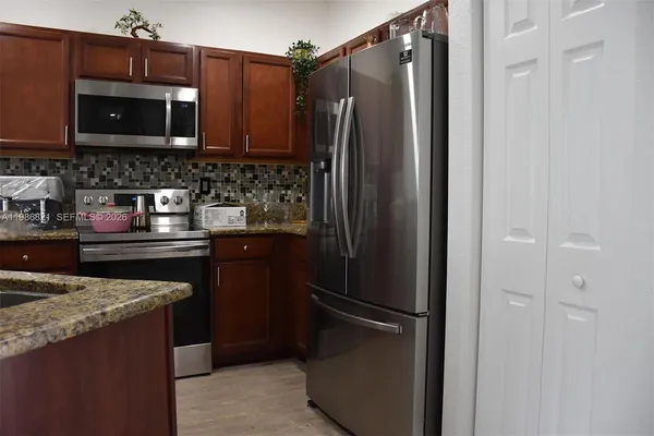 a kitchen with stainless steel appliances granite countertop a refrigerator and a microwave