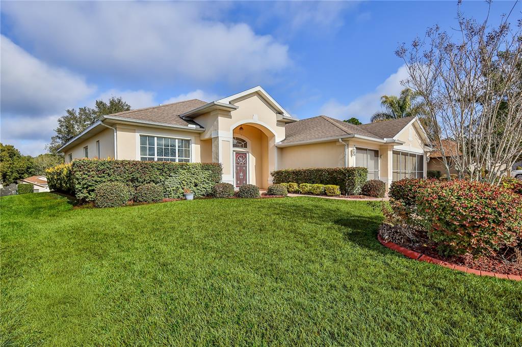 239 Longleaf Court Spring Hill, FL 34609 - Photo 3 of 55 a front view of a house with a garden and trees