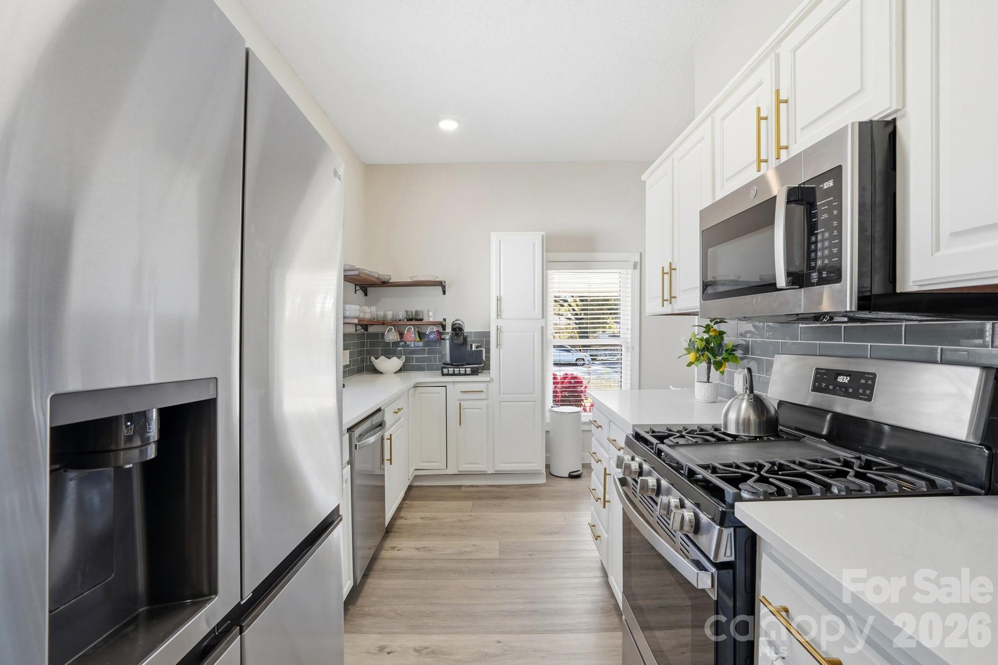 128 Massey Street Fort Mill, SC 29715 - Photo 6 of 29 a kitchen with stainless steel appliances a stove top oven a sink a refrigerator white cabinets and wooden floor