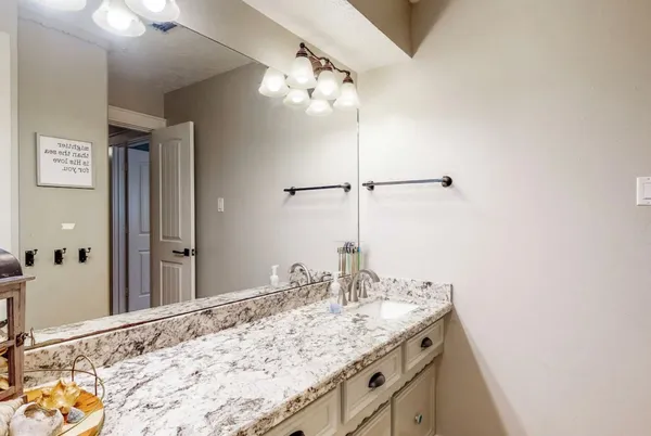 a bathroom with a granite countertop sink a large mirror and vanity
