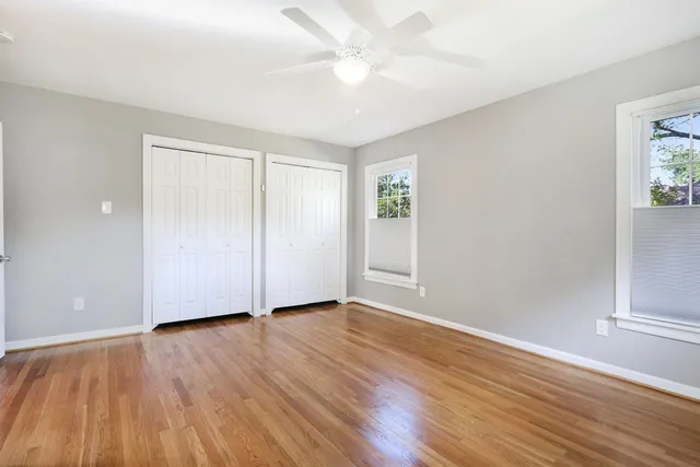 an empty room with wooden floor and windows