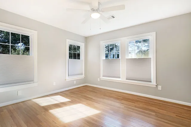 a view of an empty room with window and wooden floor