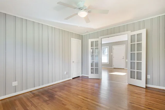 a view of an empty room with wooden floor and a window