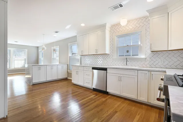 a kitchen with stainless steel appliances granite countertop a sink cabinets and wooden floor
