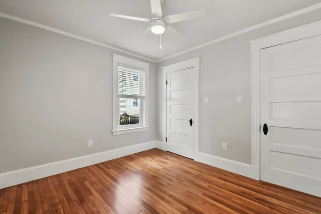 an empty room with wooden floor cabinet and windows