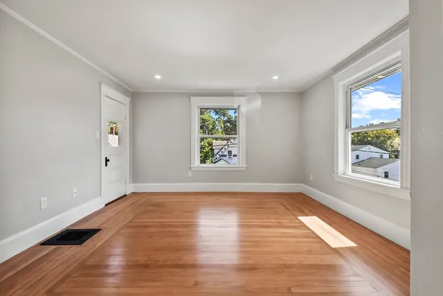 a view of an empty room with wooden floor and a window