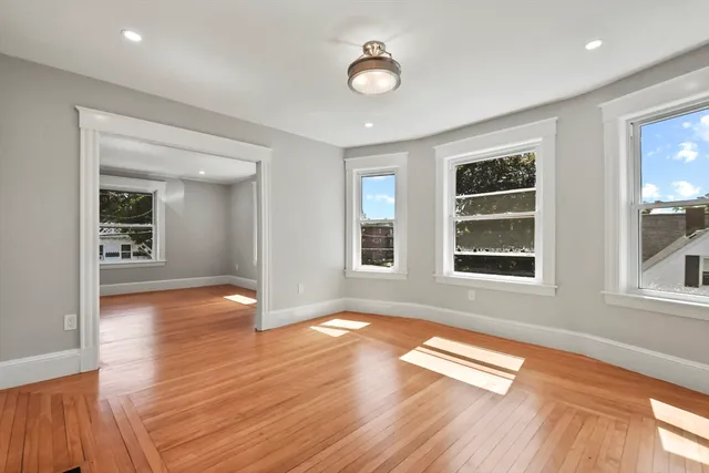 a view of empty room with wooden floor and fan