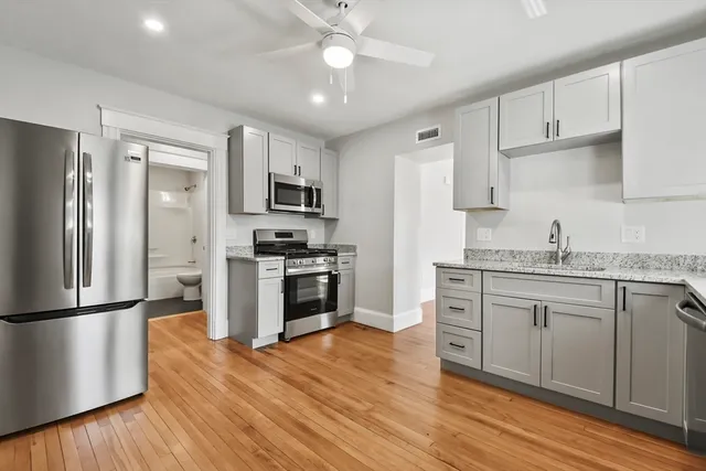 a kitchen with granite countertop a refrigerator stove a sink and dishwasher with wooden floor