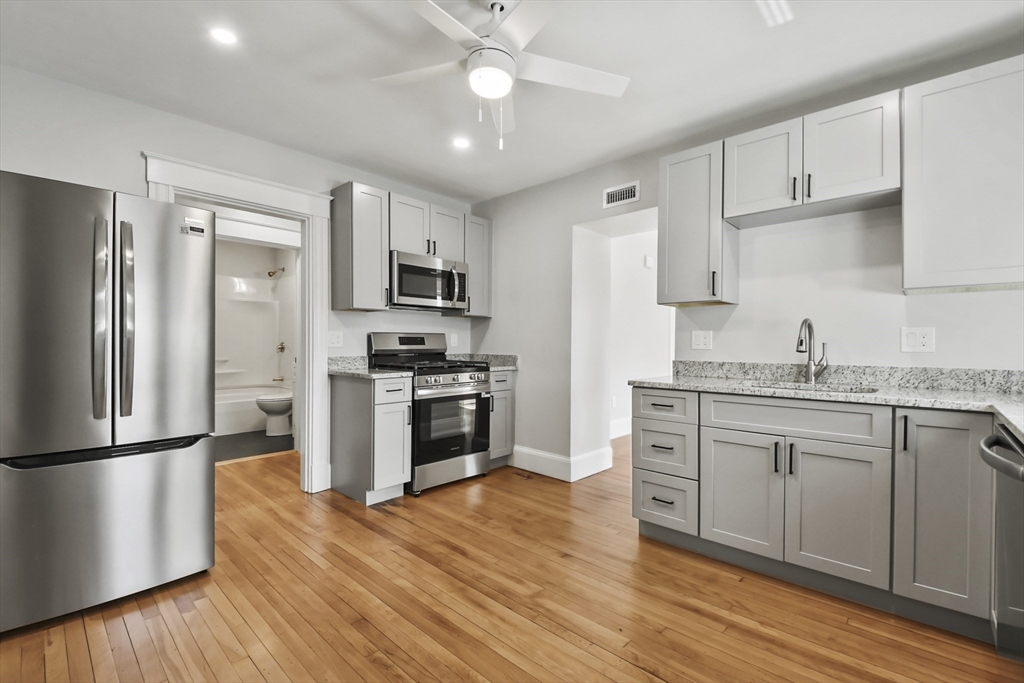 10 Cain Avenue, Unit 10 Weymouth, MA 02189 - Photo 22 of 34 a kitchen with granite countertop a refrigerator stove a sink and dishwasher with wooden floor