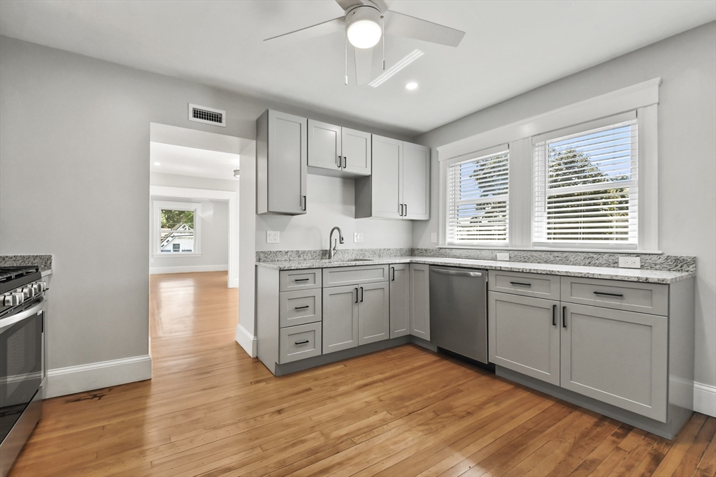 10 Cain Avenue, Unit 10 Weymouth, MA 02189 - Photo 23 of 34 a kitchen with stainless steel appliances granite countertop a stove a sink and white cabinets with wooden floor