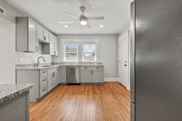 a large kitchen with granite countertop a large counter top space a sink stainless steel appliances and cabinets