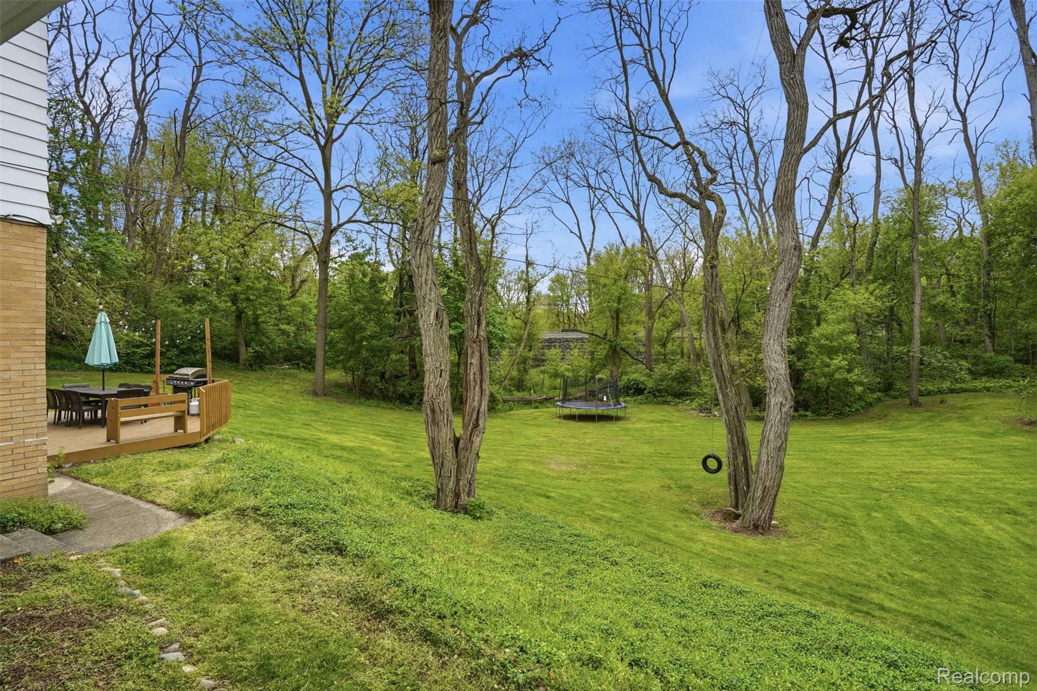 47129 Dunsany Road Northville, MI 48167 - Photo 40 of 49 View of green lawn featuring a trampoline and a deck