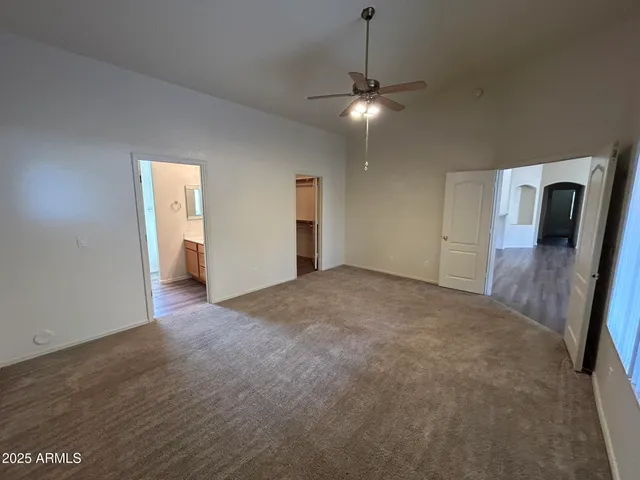 an empty room with chandelier fan and windows
