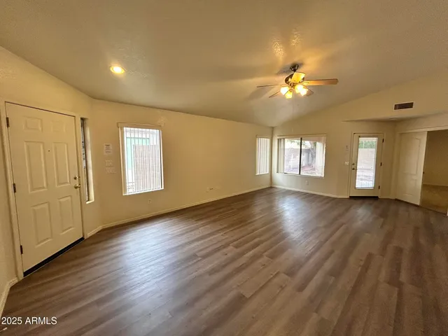 a view of an empty room with a window and wooden floor