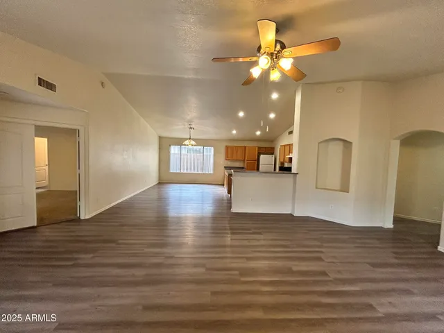 a view of an empty room with wooden floor and a ceiling fan