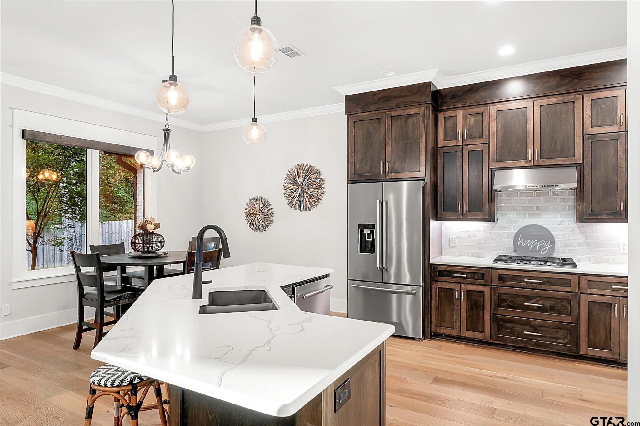 4301 Windrush Boulevard Longview, TX 75604 - Photo 11 of 36 a kitchen with stainless steel appliances a stove a refrigerator a sink a dining table and chairs with wooden floor