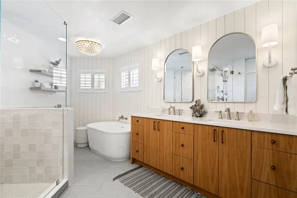 a spacious bathroom with a double vanity sink a mirror and a bathtub