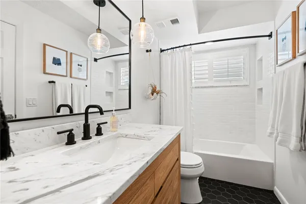 a bathroom with a granite countertop sink a toilet and shower